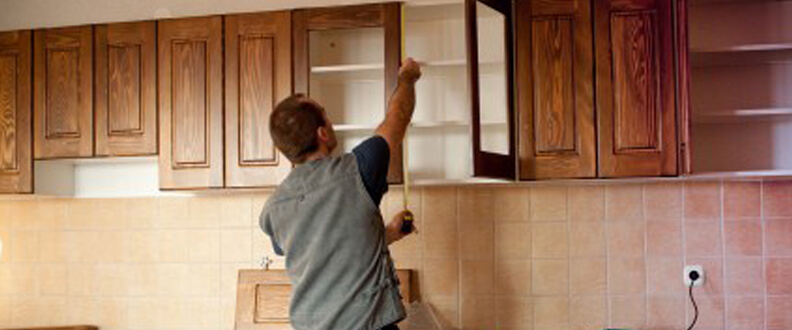 This image shows a man measuring a cabinet.