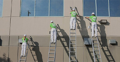 This image shows a group of men painting a commercial building.