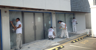 This image shows a group of men painting a commercial building.