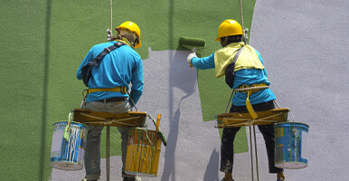This image shows 2 men painting the wall of a house.