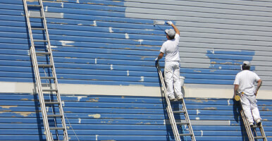 This image shows men using a roller brush to paint a wall.
